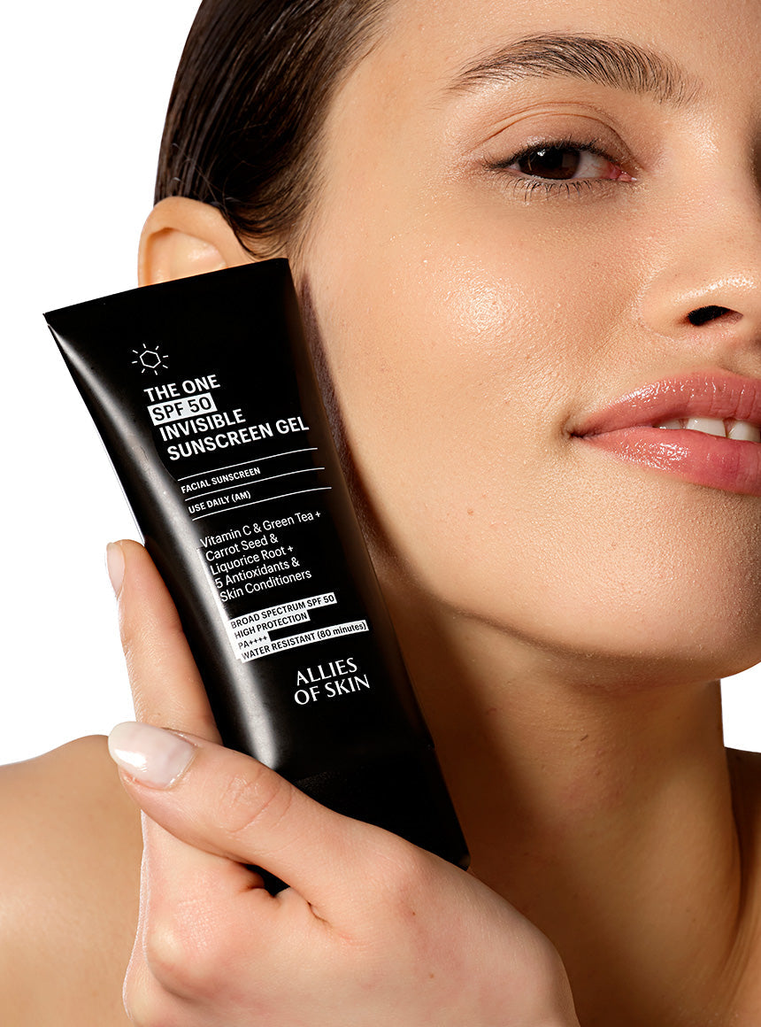 Person holding a tube of Allies of Skin sunscreen gel close to their face.